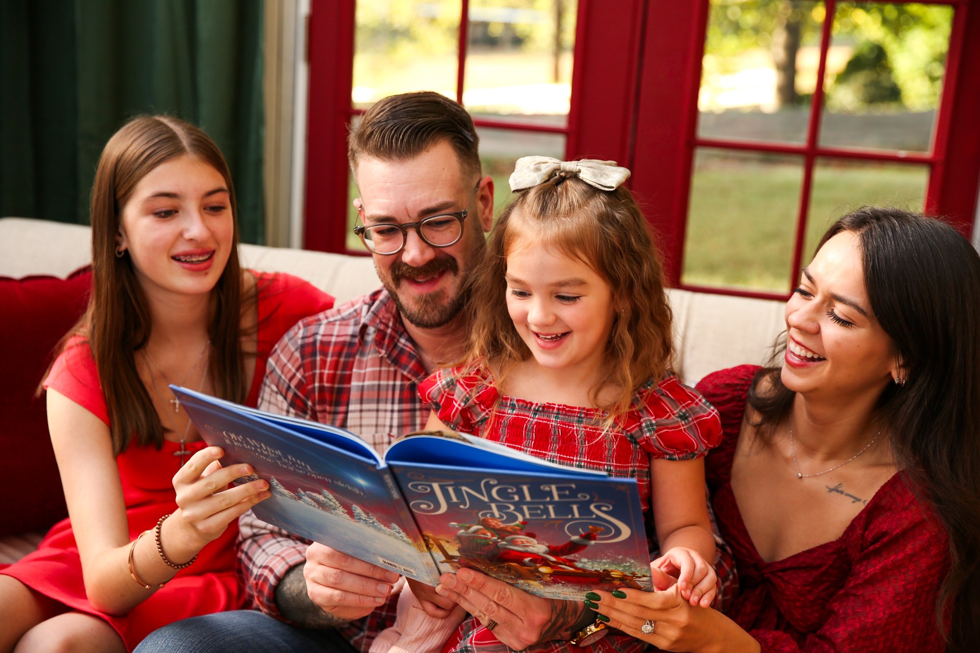 A father and daughters reading a Christmas book
