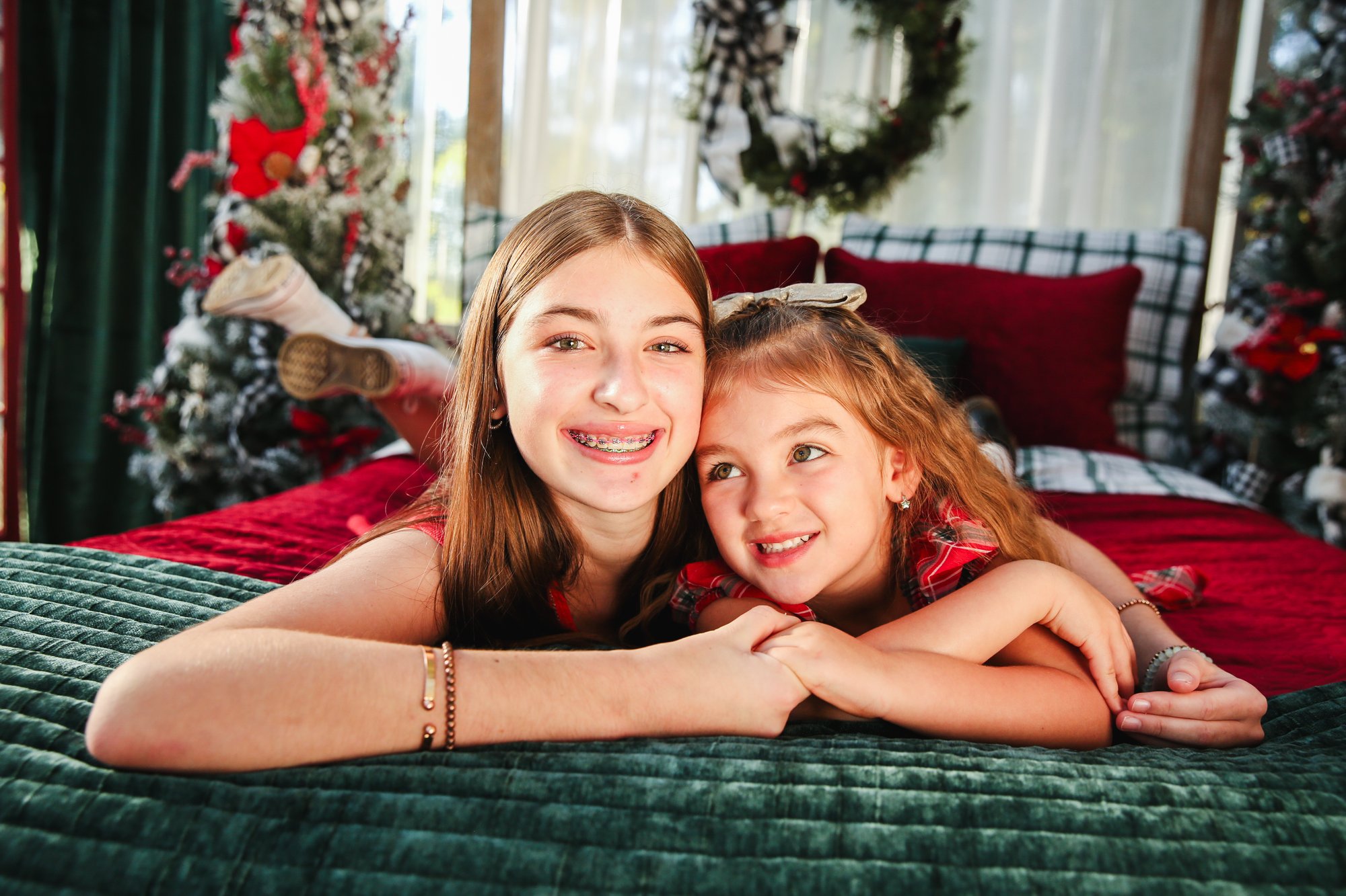 Two sisters smiling together on a velvet bed