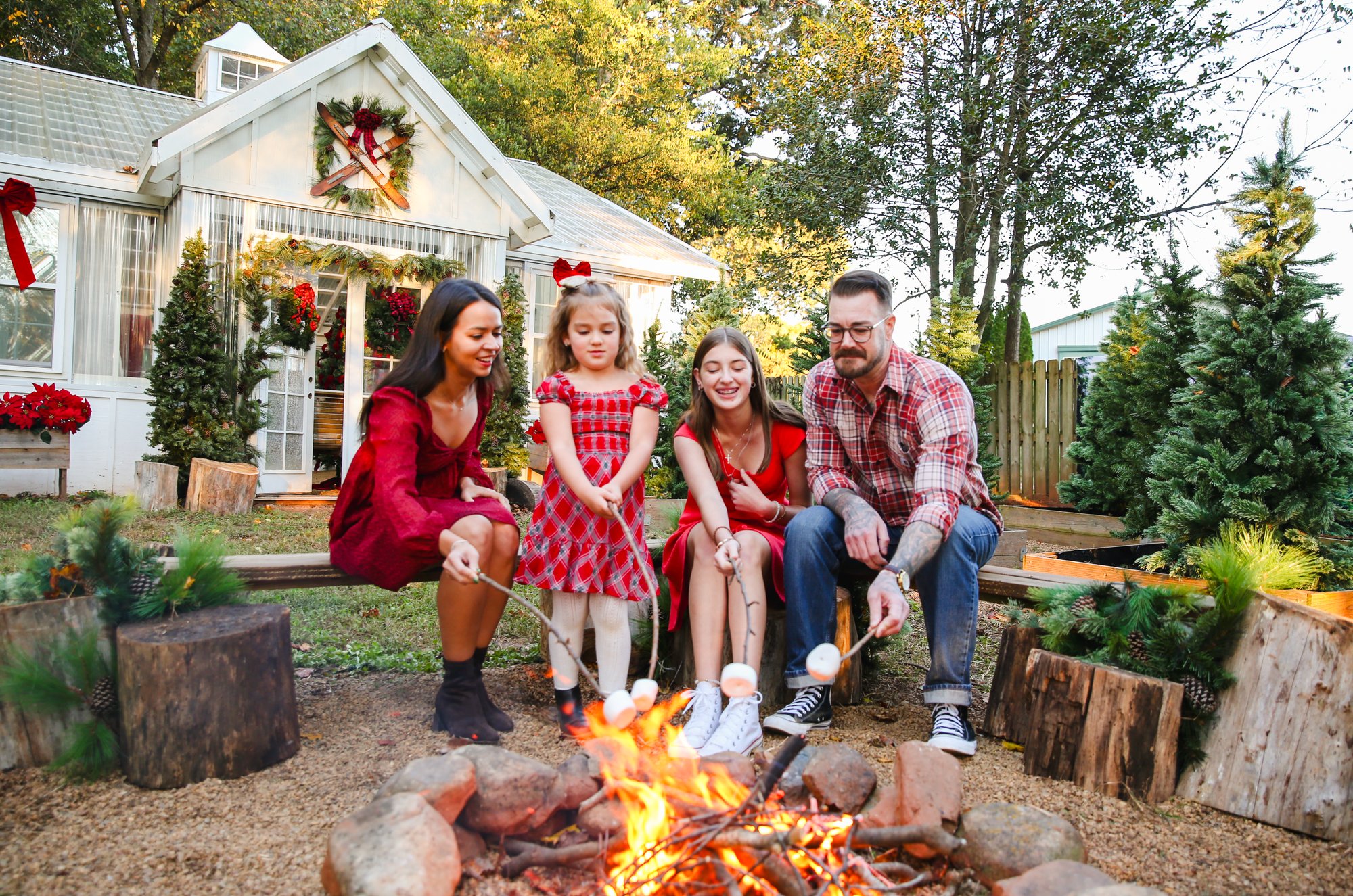 A family toasting marshmallows by the fire outside the greenhouse