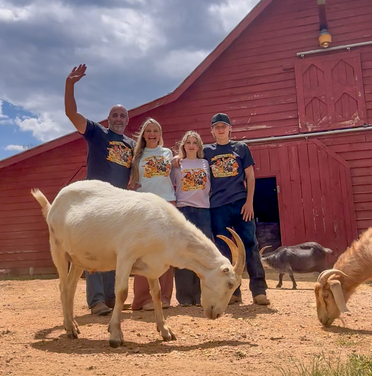 The Storybook Tails family in front of the red barn with rescued goats