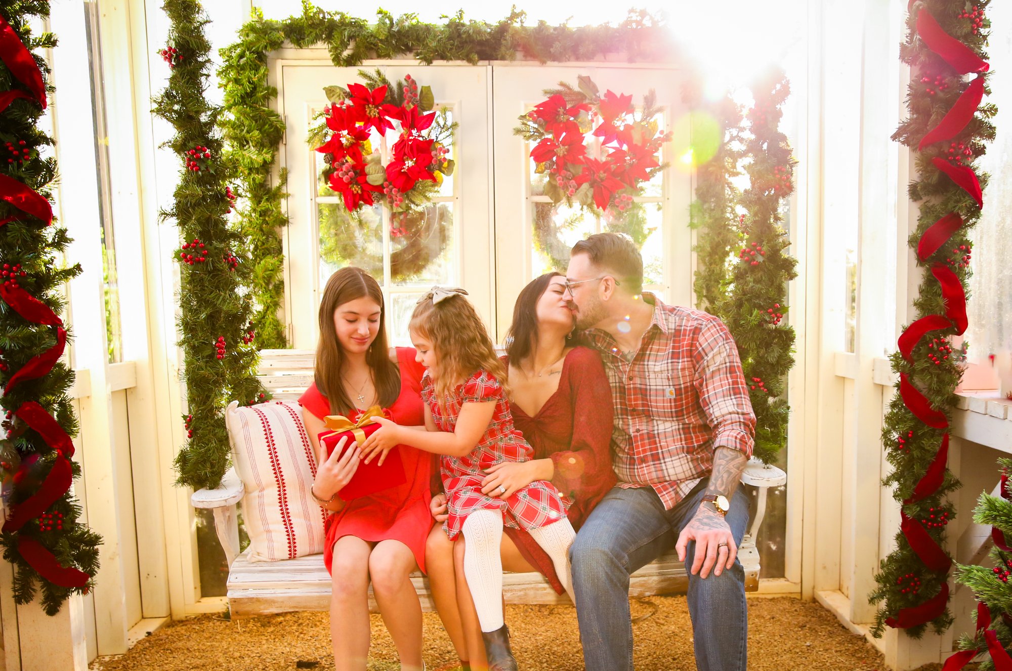 A family on a swing in front of the wreath-hung greenhouse doors